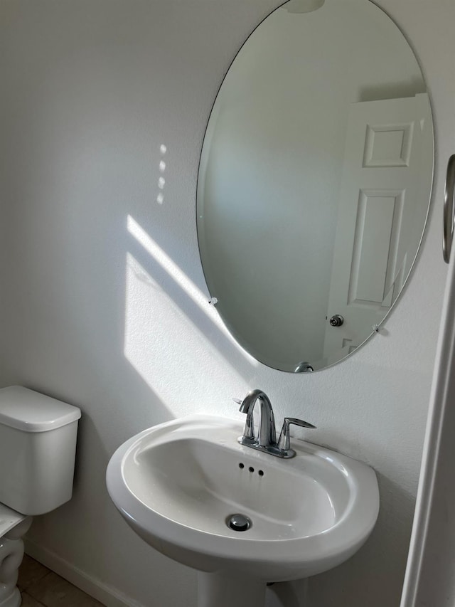 bathroom featuring baseboards, a sink, and toilet