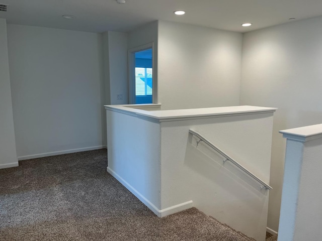 interior space with visible vents, baseboards, an upstairs landing, dark carpet, and recessed lighting