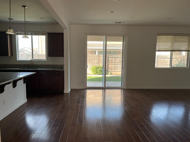 kitchen with a healthy amount of sunlight, dark countertops, a sink, and pendant lighting