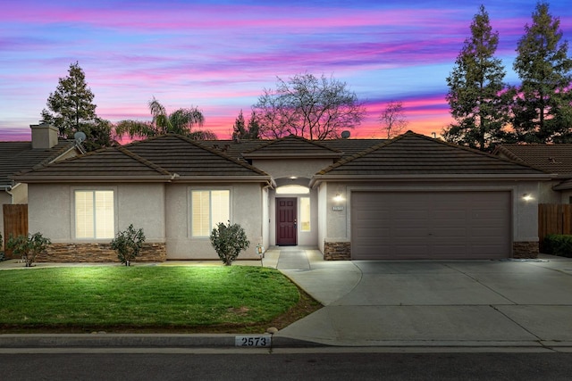 ranch-style house featuring driveway, stone siding, an attached garage, a front lawn, and stucco siding