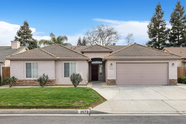 single story home with concrete driveway, stone siding, a tile roof, an attached garage, and a front yard