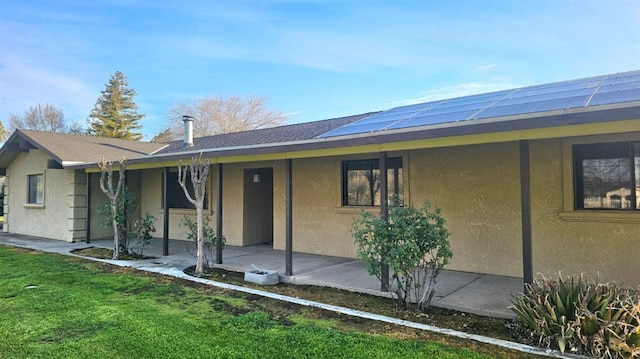 exterior space with a front lawn, a patio area, and stucco siding