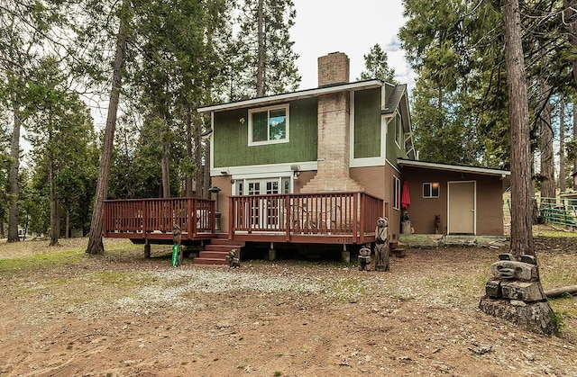 rear view of house with a chimney, a wooden deck, and stucco siding