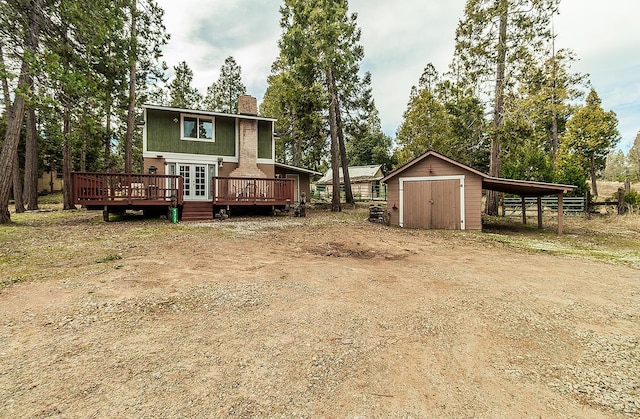 back of property featuring a chimney, a storage unit, a deck, a carport, and an outdoor structure