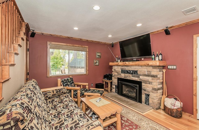 living area featuring a textured ceiling, recessed lighting, a fireplace, visible vents, and light wood-type flooring