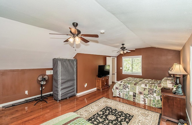 bedroom with a ceiling fan, lofted ceiling, baseboards, and wood finished floors