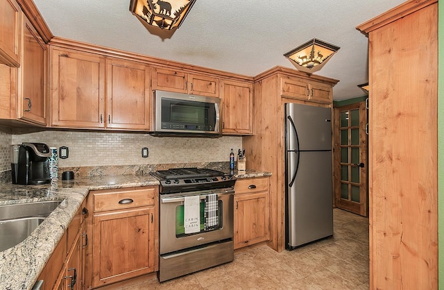 kitchen featuring brown cabinets, light stone countertops, and stainless steel appliances