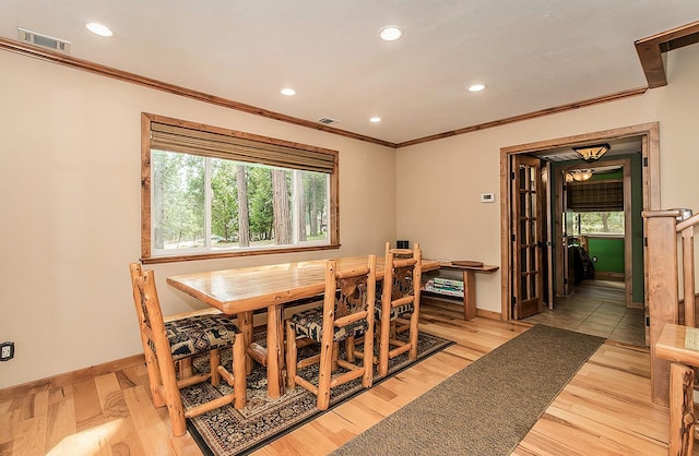 dining area with baseboards, visible vents, crown molding, and light wood finished floors