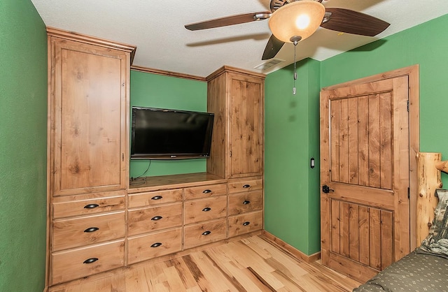 bedroom featuring light wood finished floors, visible vents, baseboards, ceiling fan, and a textured ceiling