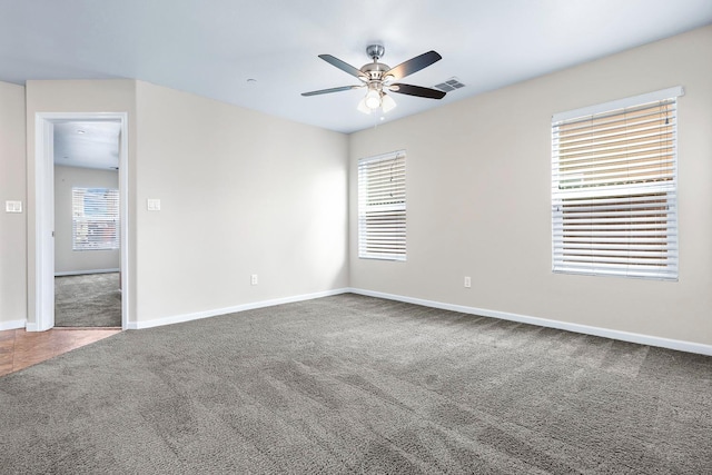 carpeted spare room featuring baseboards, visible vents, and a ceiling fan