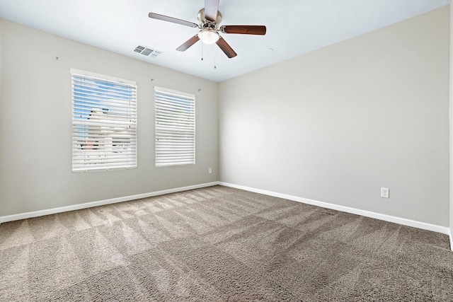 empty room with carpet floors, baseboards, visible vents, and a ceiling fan