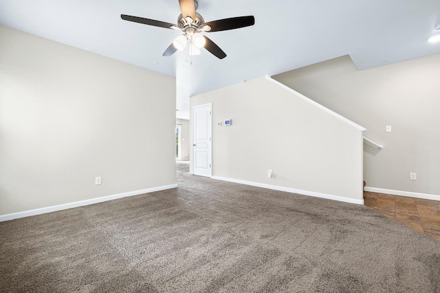 unfurnished living room with baseboards, dark carpet, and ceiling fan