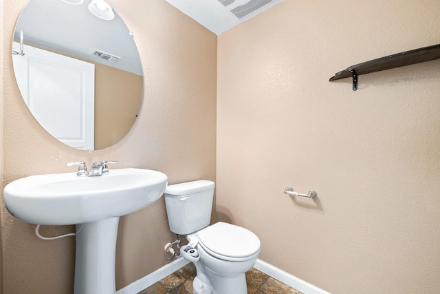 bathroom featuring toilet, visible vents, and baseboards