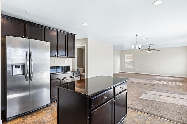 kitchen featuring a center island, open floor plan, stone finish flooring, dark brown cabinets, and stainless steel fridge