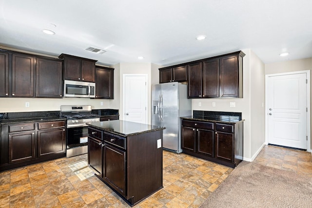 kitchen featuring stainless steel appliances, visible vents, dark brown cabinets, a center island, and dark countertops