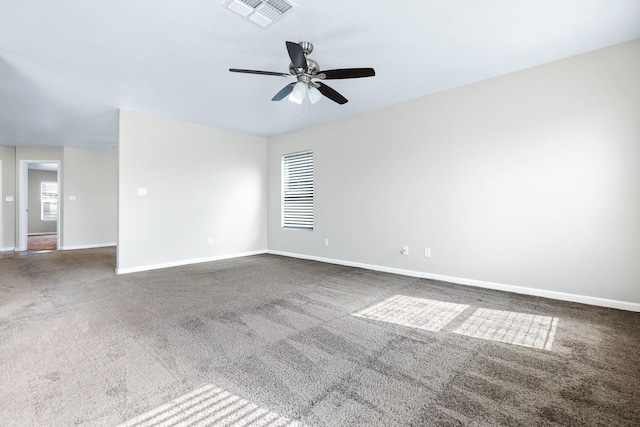 spare room with baseboards, visible vents, and dark colored carpet