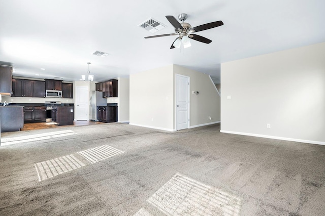 unfurnished living room with carpet floors, baseboards, visible vents, and ceiling fan with notable chandelier