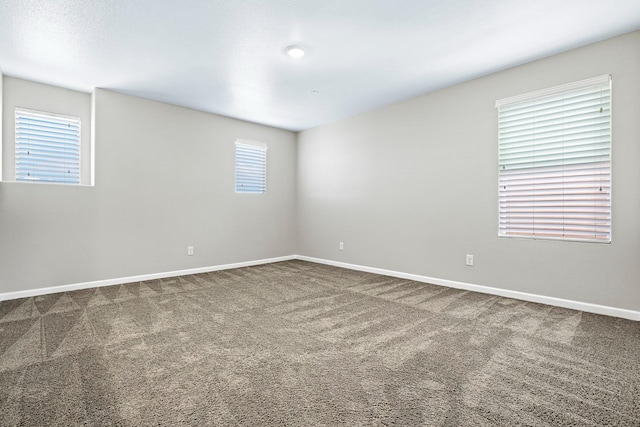 unfurnished room featuring a wealth of natural light, carpet flooring, and baseboards