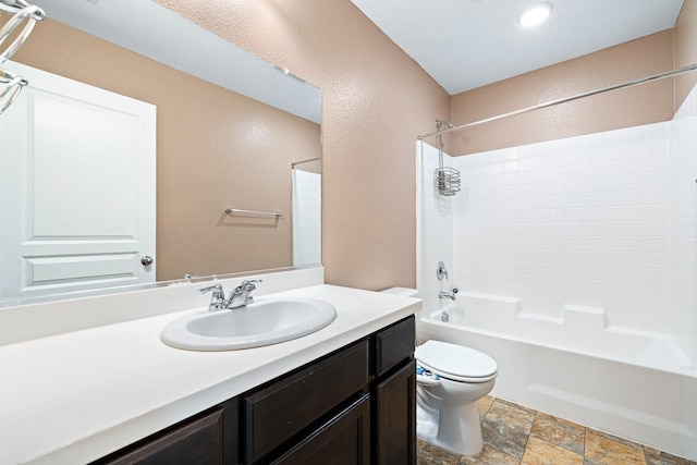 bathroom with shower / bathtub combination, a textured wall, toilet, vanity, and stone finish flooring