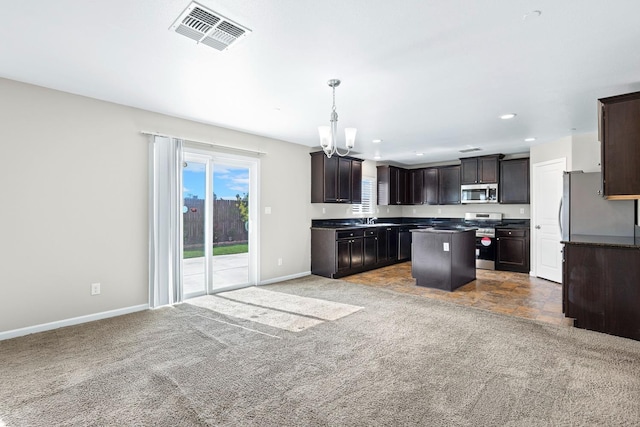 kitchen with a center island, stainless steel appliances, dark countertops, visible vents, and hanging light fixtures