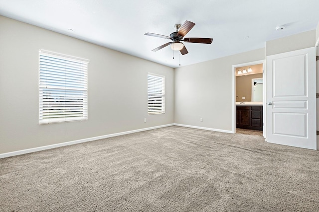 unfurnished bedroom featuring baseboards, connected bathroom, a ceiling fan, and light colored carpet