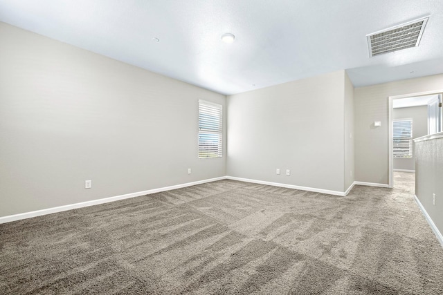 empty room featuring carpet, visible vents, and baseboards