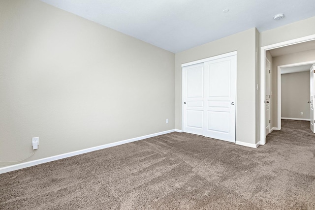 unfurnished bedroom featuring a closet, baseboards, and carpet flooring