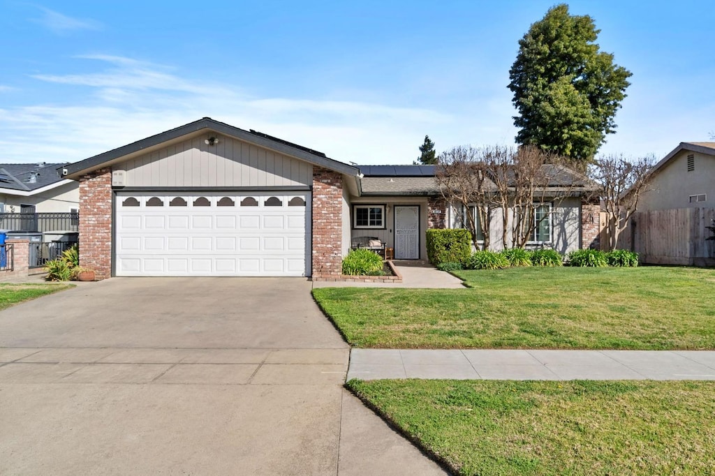 4172 N Cecelia Ave, Fresno, CA 93722 - view of front of home featuring driveway, brick siding, solar panels, an attached garage, and a front yard