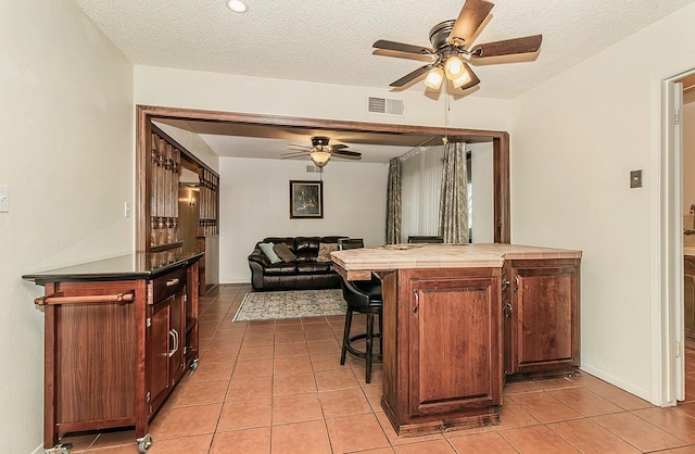 kitchen with open floor plan, visible vents, a breakfast bar area, and light tile patterned flooring