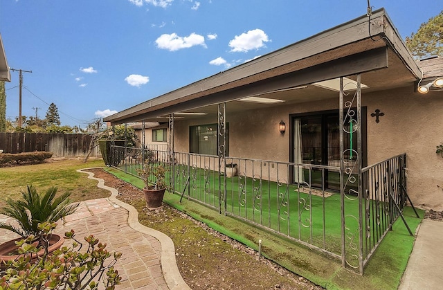 exterior space featuring fence, a lawn, and stucco siding