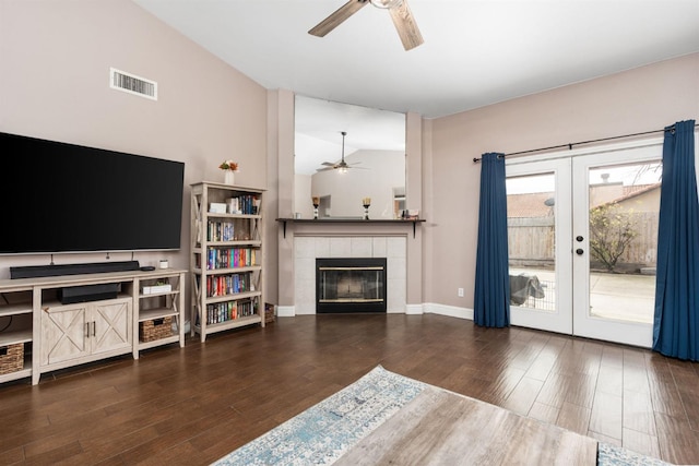 living room with french doors, a fireplace, visible vents, dark wood-type flooring, and a ceiling fan