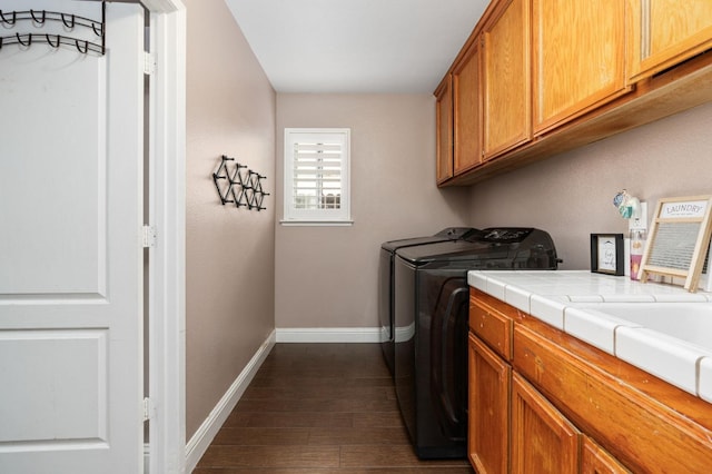 laundry area featuring cabinet space, baseboards, separate washer and dryer, and dark wood-type flooring