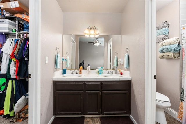 full bath with a spacious closet, double vanity, a sink, and toilet