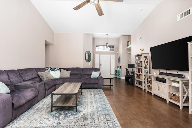 living area featuring ceiling fan, a high ceiling, dark wood finished floors, and visible vents