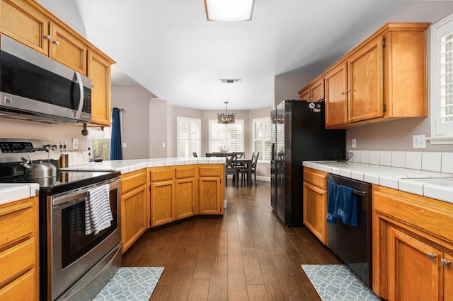 kitchen featuring stainless steel appliances, tile counters, visible vents, and hanging light fixtures