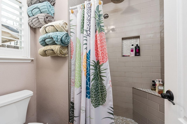 bathroom with tiled shower, a textured wall, and toilet