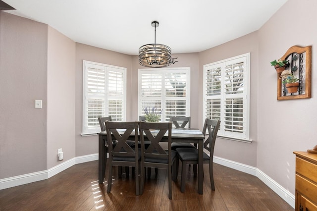 dining space featuring dark wood-style floors, baseboards, and a notable chandelier