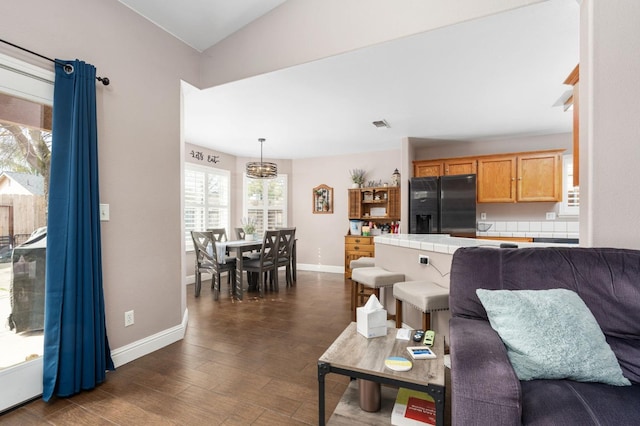 living area with dark wood-type flooring, visible vents, and baseboards