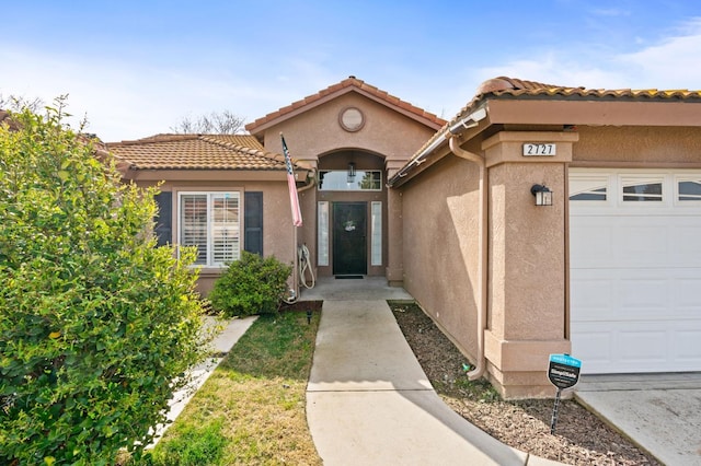 property entrance with a garage and stucco siding