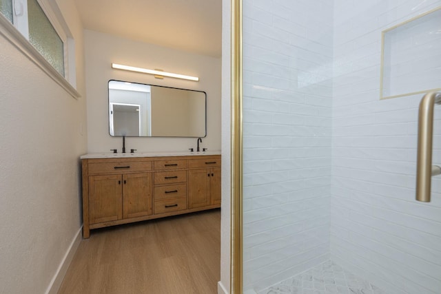 bathroom with double vanity, a sink, baseboards, and wood finished floors