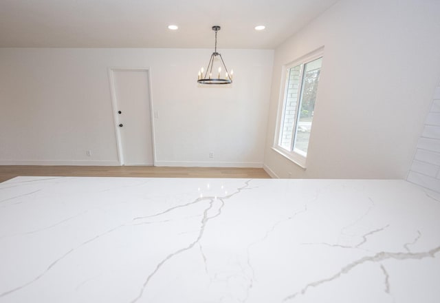 spare room with a chandelier, light wood-type flooring, baseboards, and recessed lighting