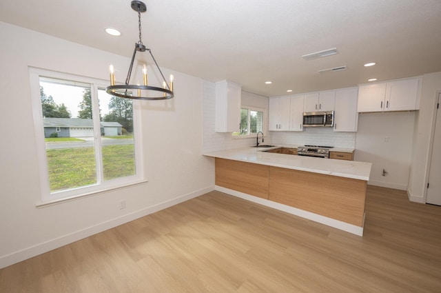 kitchen featuring pendant lighting, stainless steel appliances, tasteful backsplash, white cabinets, and a peninsula