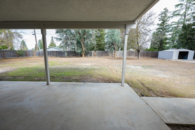 view of patio / terrace with an outbuilding, a fenced backyard, and a storage shed