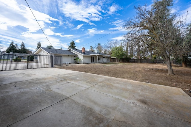 ranch-style house featuring fence, concrete driveway, stucco siding, a front lawn, and a chimney