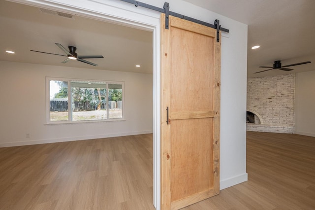 interior space featuring a barn door, baseboards, visible vents, wood finished floors, and recessed lighting