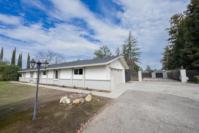 exterior space with brick siding, stucco siding, fence, a garage, and driveway