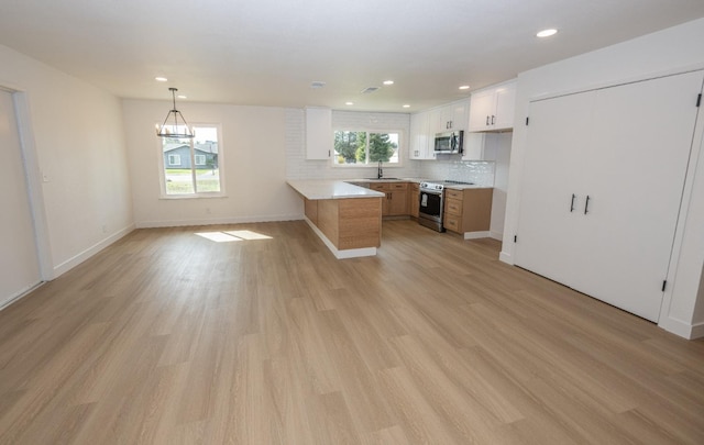 kitchen with a sink, white cabinets, open floor plan, appliances with stainless steel finishes, and plenty of natural light