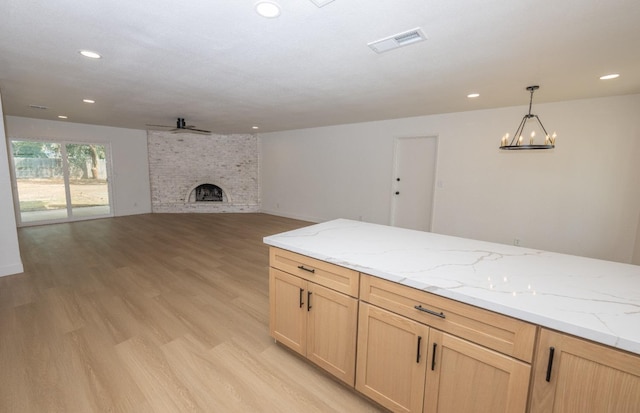 kitchen featuring visible vents, light brown cabinetry, a ceiling fan, a brick fireplace, and open floor plan