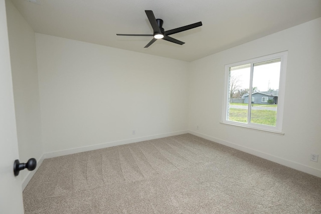 carpeted empty room featuring a ceiling fan and baseboards