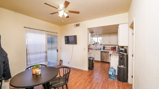 dining room featuring a ceiling fan, a textured ceiling, visible vents, and wood finished floors